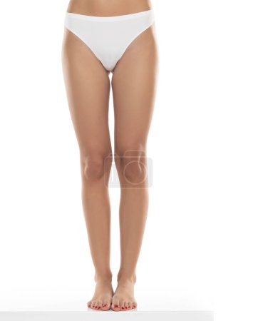 Téléchargez les photos : Jambes féminines parfaites en sous-vêtements sur fond de studio blanc. Vue de face - en image libre de droit