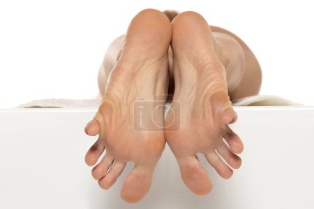 Téléchargez les photos : Gros plan d'une semelle féminine aux orteils tendus sur fond de studio blanc - en image libre de droit