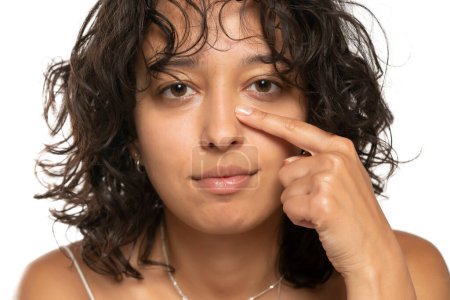 Foto de La joven etnica se toca la nariz con los dedos sobre un fondo blanco de estudio. vista frontal - Imagen libre de derechos