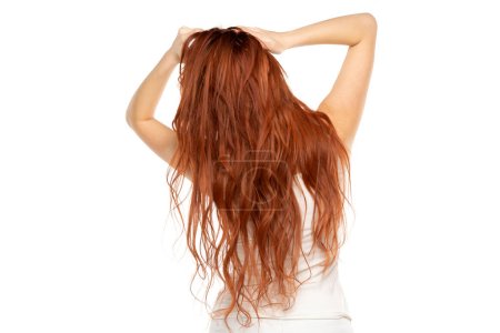 Téléchargez les photos : Vue arrière de la femme rousse avec de longs cheveux ondulés au gingembre sur un fond de studio blanc - en image libre de droit