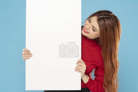 Photo for Banner of young happy redhead woman feeling happiness and holding Empty white canvas frame for text or advertising isolated on blue studio background - Royalty Free Image
