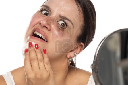 Photo for Nervous young woman  remove  the makeup on a white studio background - Royalty Free Image