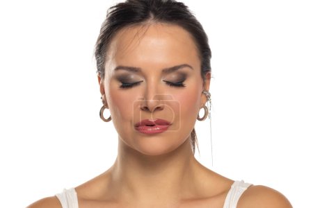Téléchargez les photos : Portrait de belle femme avec maquillage et les yeux fermés sur un fond de studio blanc - en image libre de droit