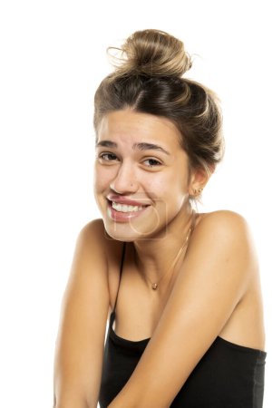 Foto de Joven mujer sonriente con moño suelto desordenado y sin maquillaje en un fondo de estudio blanco. vista lateral del perfil - Imagen libre de derechos