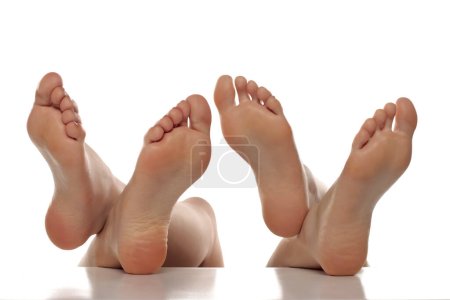 Téléchargez les photos : Deux paires de pieds uniques féminins bien entretenus sur un fond de studio isolé blanc, Le concept de soins de la peau des pieds - en image libre de droit