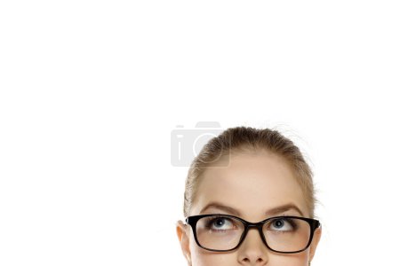 Foto de Medio retrato de una joven rubia con gafas mirando hacia arriba sobre un fondo de estudio blanco - Imagen libre de derechos