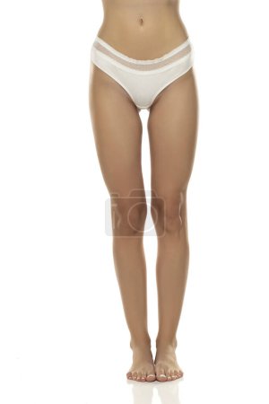 Photo for Woman's legs are elegantly posed, showcasing white panties from the front on white studio background.Femininity, sensuality, and body positivity, making it suitable for various themes in the lingerie, beauty industry. - Royalty Free Image