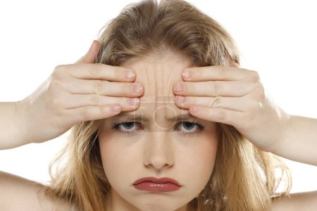 Foto de Retrato de una joven infeliz mostrando sus arrugas en la frente sobre un fondo blanco de estudio - Imagen libre de derechos