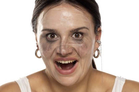 Téléchargez les photos : Femme souriante folle avec maquillage maculé sur fond de studio blanc - en image libre de droit