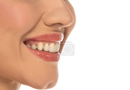 Téléchargez les photos : Gros plan, vue latérale de la bouche d'une femme, capturant un sourire confiant et des dents et lèvres naturelles parfaites sur fond de studio blanc - en image libre de droit