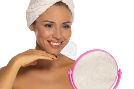 Photo for Happy confident young lady with towel on head look in the mirror touching moisturized soft healthy sensitive skin doing morning hydration spa beauty routine, facial skincare treatment concept - Royalty Free Image