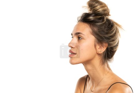 Photo for Young woman with messy loose bun and no makeup on a white studio background. side profile view - Royalty Free Image