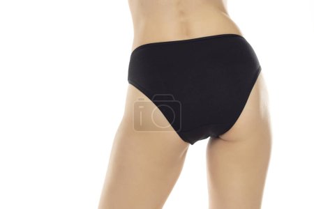 Photo for The elegance of women's bac is showcased as she stands confidently in black panties, exuding a sense of style and sophistication on a white studio background. Back, rear view - Royalty Free Image