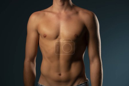 Photo for The torso of a young athletic guy. concept: the male body after exercise and diet. men's health: shaved breasts on a dark studio background - Royalty Free Image