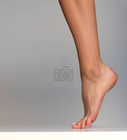 Photo for Closeup shot of healthy beautiful female feet. Health and beauty concept. Side view of human foot on grey studio background - Royalty Free Image