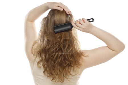 Téléchargez les photos : Dos, vue arrière d'une jeune femme brossant des cheveux sains sur un fond de studio blanc - en image libre de droit
