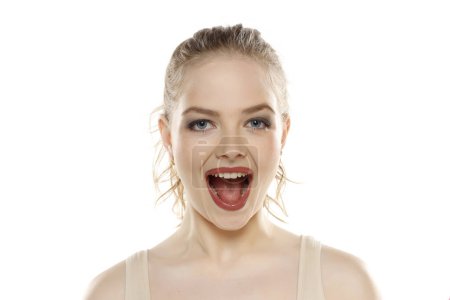 Téléchargez les photos : Portrait de jeune femme blonde heureuse beautifu avec maquillage et cheveux attachés sur fond de studio blanc - en image libre de droit
