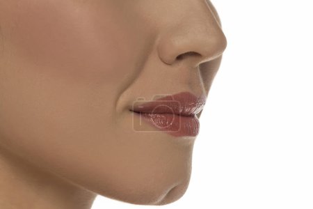 Téléchargez les photos : Gros plan, vue latérale de la bouche d'une femme sur fond de studio blanc - en image libre de droit