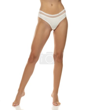 Photo for Woman's legs are elegantly posed, showcasing white panties from the front on white studio background.Femininity, sensuality, and body positivity, making it suitable for various themes in the lingerie, beauty industry. - Royalty Free Image