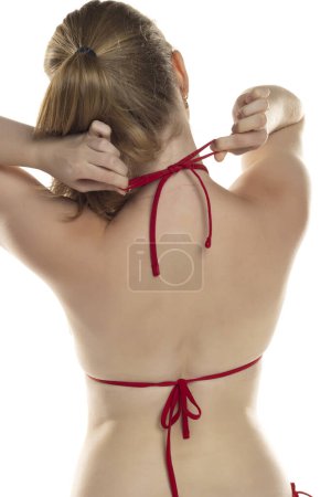 Téléchargez les photos : Femme attachant haut de bikini sur un fond de studio blanc - en image libre de droit