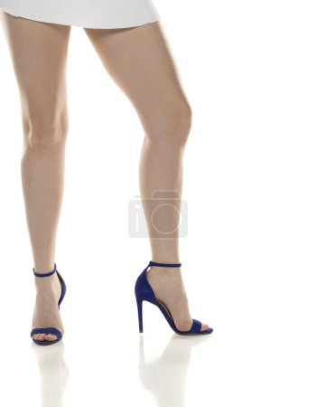 Photo for Close up of woman legs in high heeled sandals.White short dress on white studio background. - Royalty Free Image