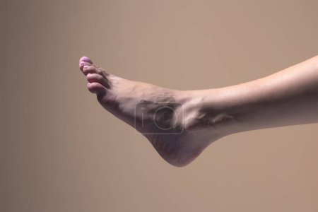 Téléchargez les photos : Gros plan pieds féminins nus sur un fond studio beige - en image libre de droit