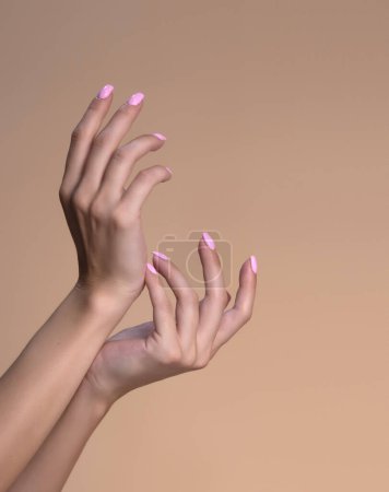 Téléchargez les photos : Concept beauté et soins de la peau - belles mains féminines, femme touchant la peau après un soin spa isolé sur fond beige studio, gros plan - en image libre de droit