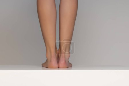 Photo for Pretty woman bare feet and heels on gray studio background - Royalty Free Image