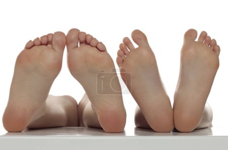 Téléchargez les photos : Deux paires de pieds uniques féminins bien entretenus sur un fond de studio isolé blanc, Le concept de soins de la peau des pieds - en image libre de droit