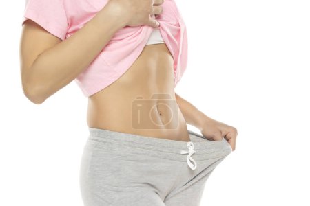 Photo for Fit woman showing flat belly on a white studio background. Closeup. - Royalty Free Image