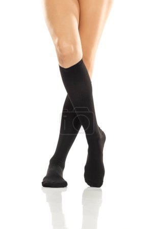 Photo for Female legs in compression Hosiery. Medical stockings, tights, socks, calves and sleeves for varicose veins and venouse therapy. Clinical knits. Sock for sports isolated on white studio background - Royalty Free Image