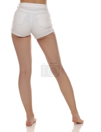 Photo for Close up photo of barefoot woman wearing white jeans on white studio background. Rear view - Royalty Free Image
