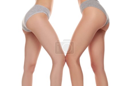 Foto de Dos pares de hermosas piernas de mujer bien arregladas de cerca sobre un fondo de estudio aislado blanco - Imagen libre de derechos