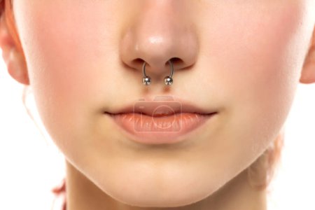 Photo for Closeup of a young serious woman's visage with piercing septum hanging from her nose. - Royalty Free Image