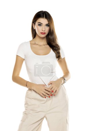 Photo for Cute brunette woman in white shirt and loose white trousers posing on a white studio background - Royalty Free Image