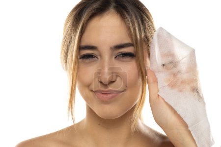 Foto de Atractiva joven mujer mostrando tejido sucio de la limpieza de su cara en un fondo de estudio blanco - Imagen libre de derechos