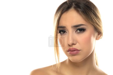 Photo for Portrait of young beautiful sad blonde woman with makeup and tied hair on white studio background - Royalty Free Image