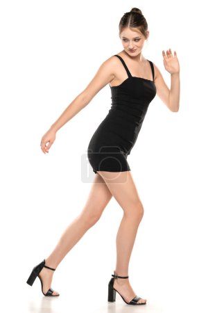 Foto de Summer Chic: Retrato completo de una mujer joven posando en un vestido corto y sandalias sobre fondo blanco de estudio - Imagen libre de derechos