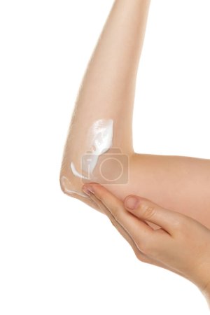 Closeup photo of woman applying moisturizer on elbow skin, care for dry elbow skin on white studio background