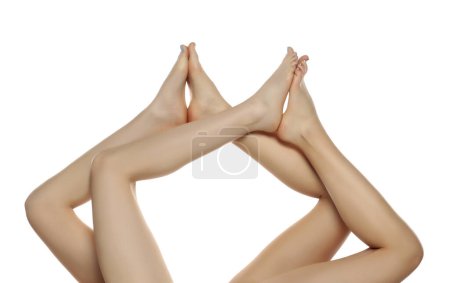 Téléchargez les photos : Deux paires de jambes de belle femme bien entretenues en gros plan sur un fond de studio isolé blanc, Le concept de l'épilation des soins de la peau des pieds - en image libre de droit
