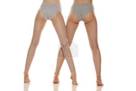 Téléchargez les photos : Deux paires de belles jambes de femme bien entretenues en gros plan sur un fond de studio isolé blanc, vue de dos - en image libre de droit