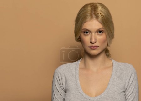 Photo for Beauty portrait of fashion young model with long tied blond hair on beige studio background - Royalty Free Image