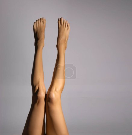 Foto de Desnudo piernas femeninas, vista superior sobre un fondo gris estudio. - Imagen libre de derechos