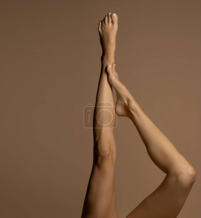 Foto de Desnudo piernas femeninas, vista superior sobre un fondo de estudio beige. - Imagen libre de derechos