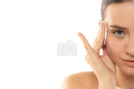 Foto de Medio retrato de una joven mujer quitándose el maquillaje sobre un fondo blanco de estudio - Imagen libre de derechos