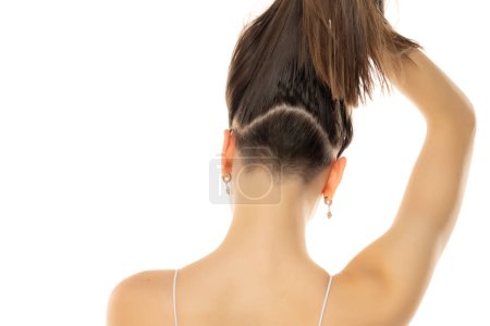 Foto de Vista trasera de una joven mujer moderna con cabeza parcialmente afeitada y cola de caballo sobre un fondo de estudio blanco - Imagen libre de derechos