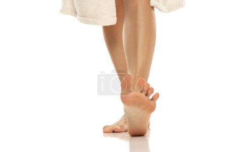 Téléchargez les photos : Gros plan de pieds nus féminins debout sur fond de studio blanc - en image libre de droit