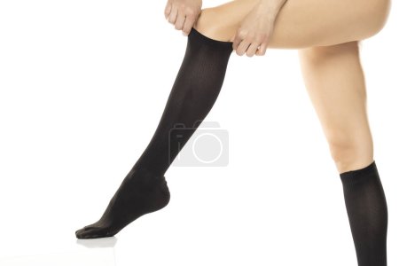 Photo for Woman wearing compression Hosiery. Medical stockings, tights, socks, calves and sleeves for varicose veins and venouse therapy. Clinical knits. Sock for sports isolated on white studio background - Royalty Free Image