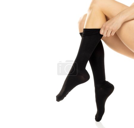 Woman wearing compression Hosiery. Medical stockings, tights, socks, calves and sleeves for varicose veins and venouse therapy. Clinical knits. Sock for sports isolated on white studio background
