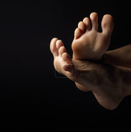 Téléchargez les photos : Gros plan, haut des pieds féminins avec les orteils posant sur fond noir studio - en image libre de droit